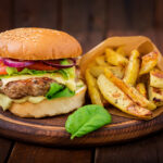 Big sandwich - hamburger with juicy beef burger, cheese, tomato,  and red onion on wooden background