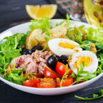Healthy hearty salad of tuna, green beans, tomatoes, eggs, potatoes, black olives close-up in a bowl on the table. Salad Nicoise. French cuisine.